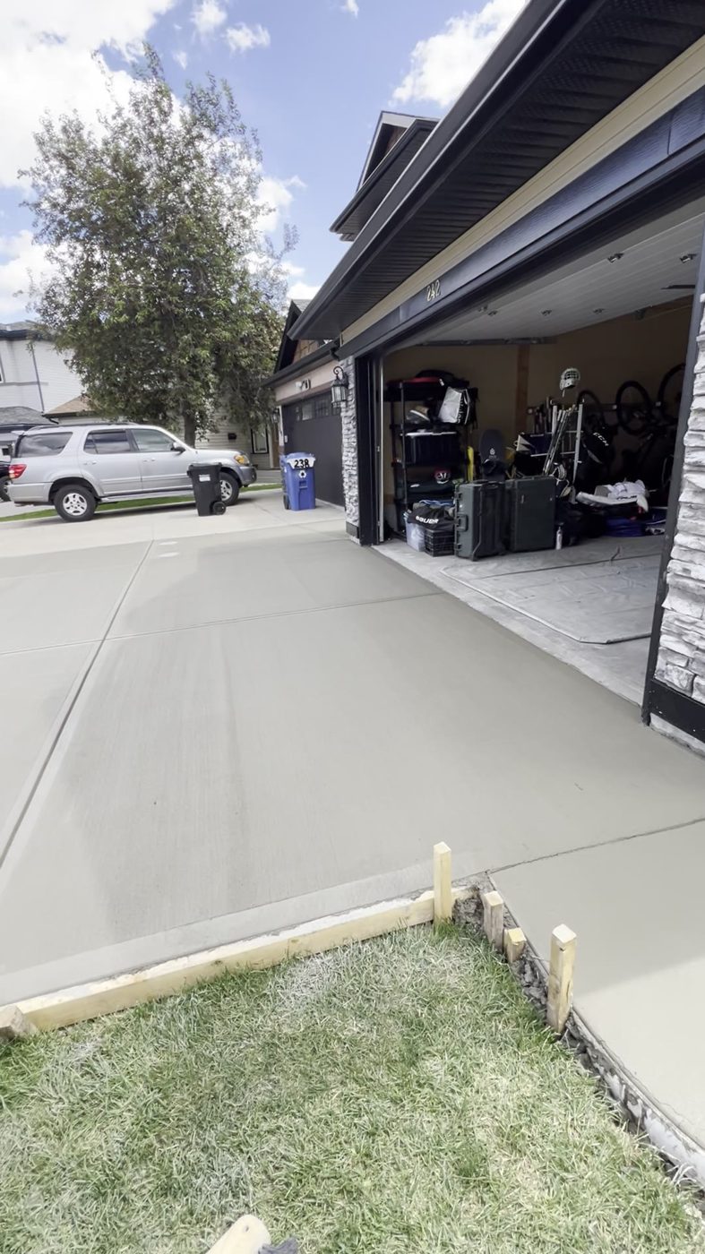 Freshly poured brushed concrete double-garage driveway with forms still in place at a Coventry Hills home in NE Calgary by Patriarch Construction