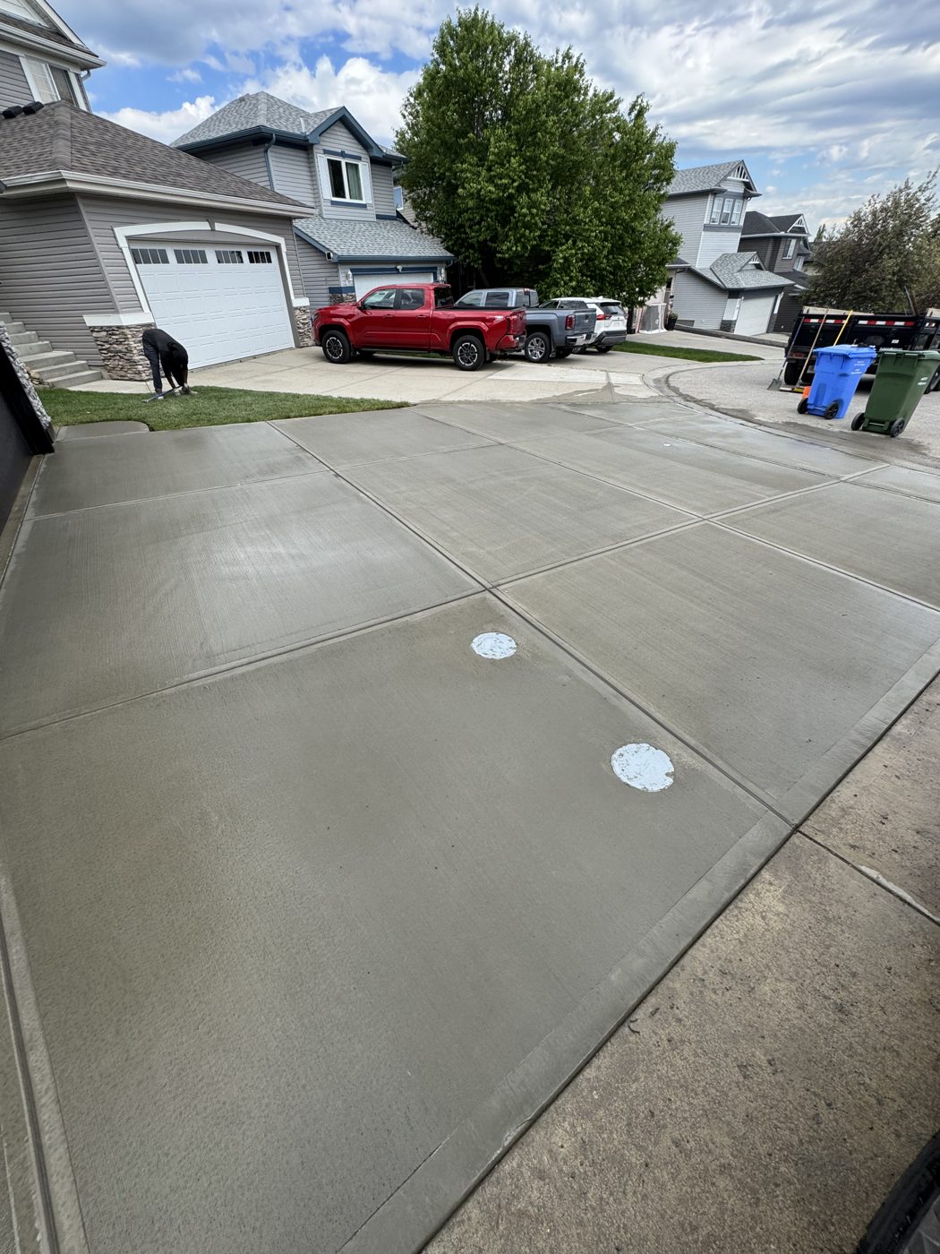 Wide freshly poured brushed concrete double-garage driveway replacement at a West Springs family home in SW Calgary by Patriarch Construction